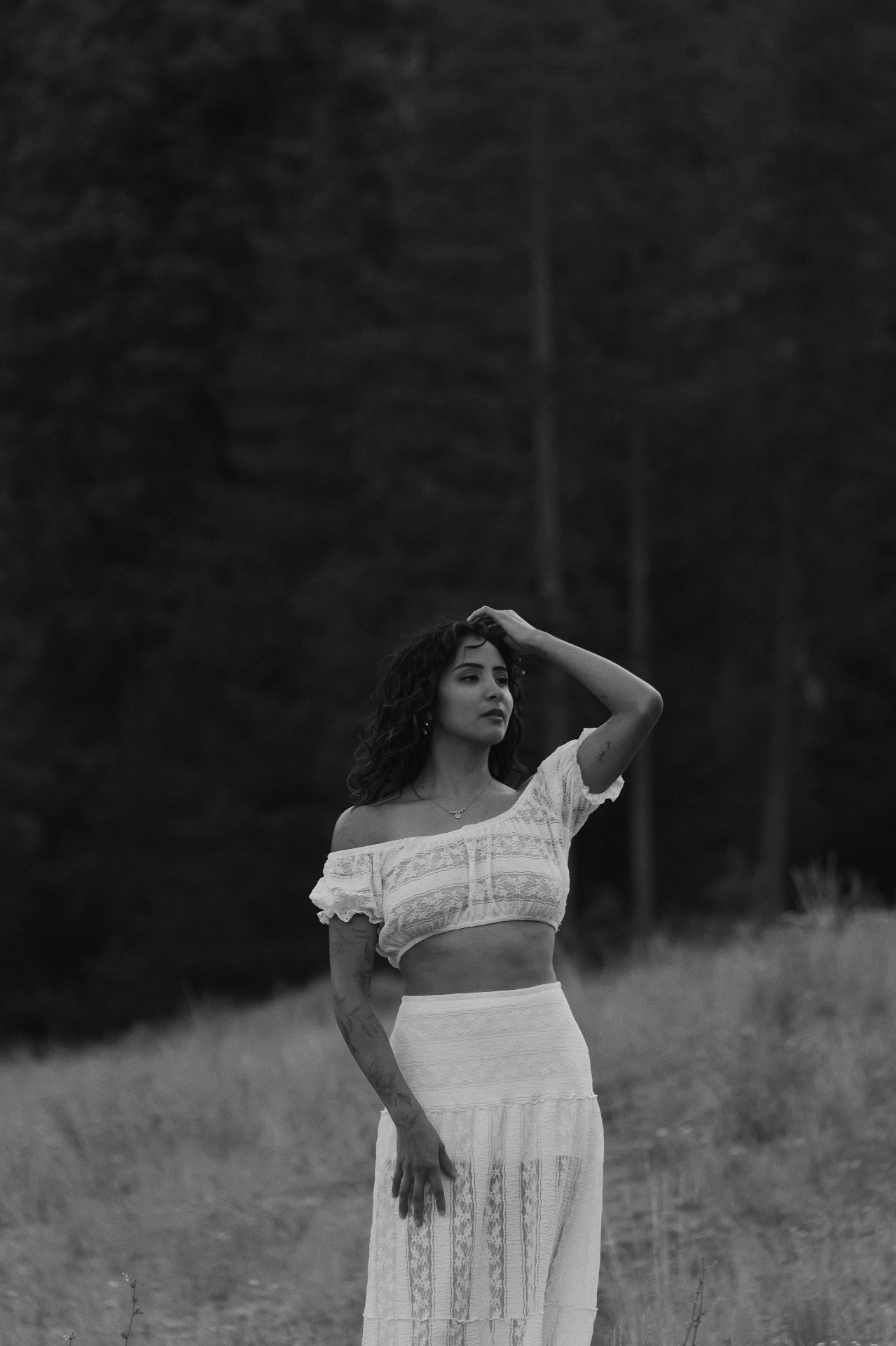 Black and white portrait of a woman in a lace dress in a meadow