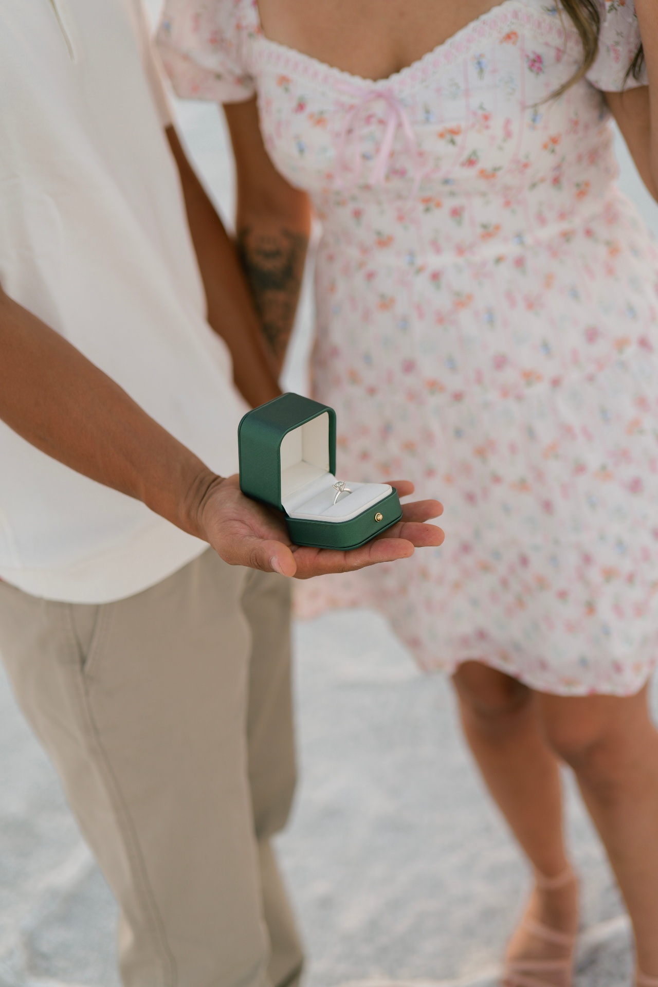 Green velvet ring box held between the couple