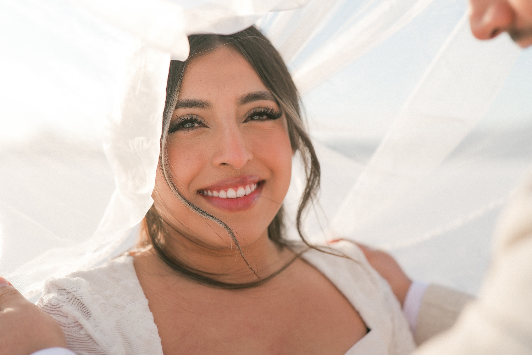 Bride smiling beneath a sunlit veil