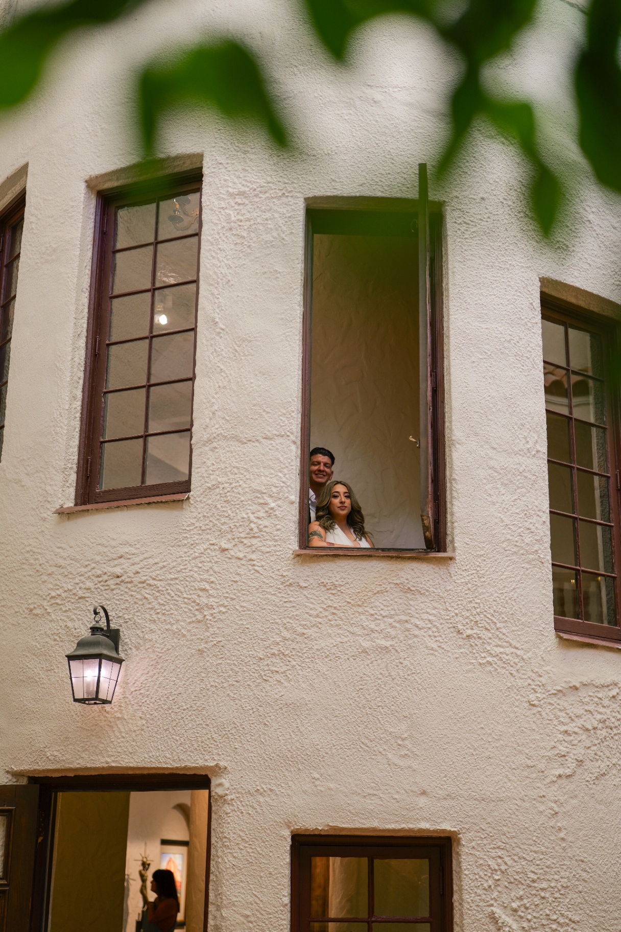 Couple looking out from a high window in a white stucco building