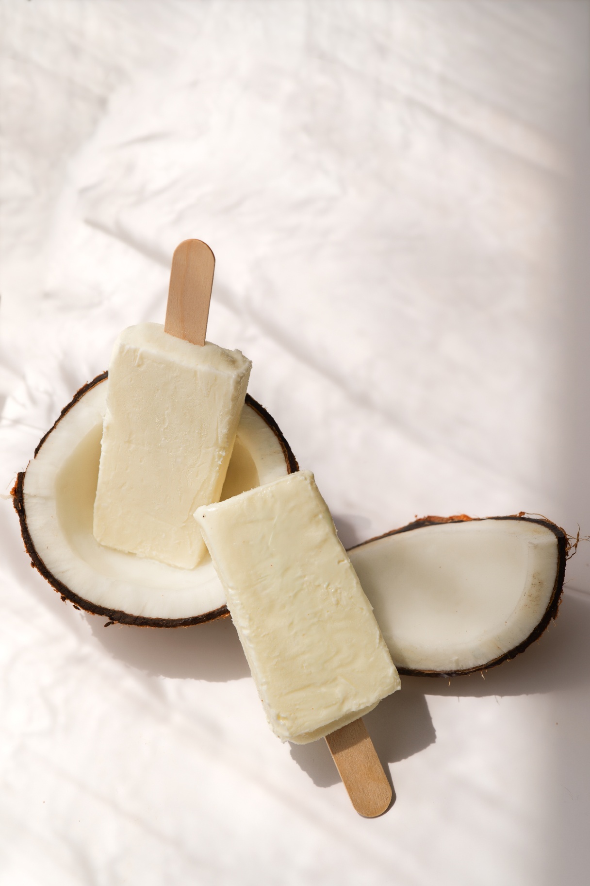 Coconut popsicles resting in a halved coconut